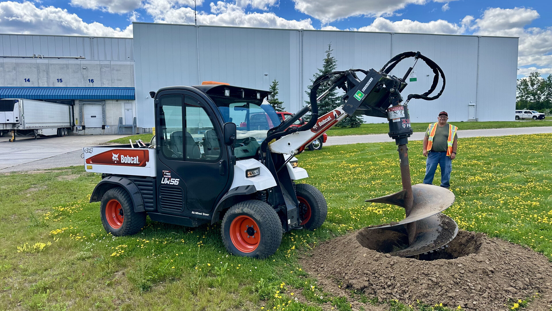 Commercial landscaping crew using a Bobcat auger at an industrial property in Brantford, Ontario.