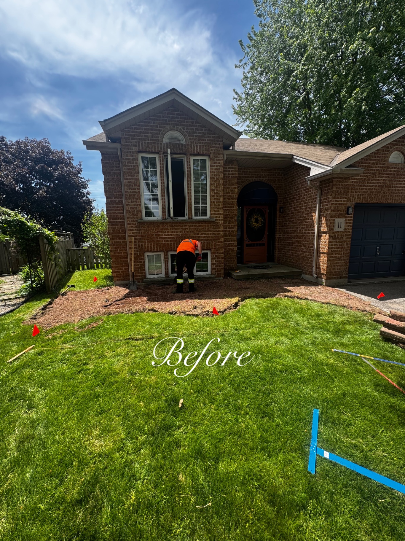 Front lawn marked out and prepped for new sod and bed re-shaping, crew member working at the house.